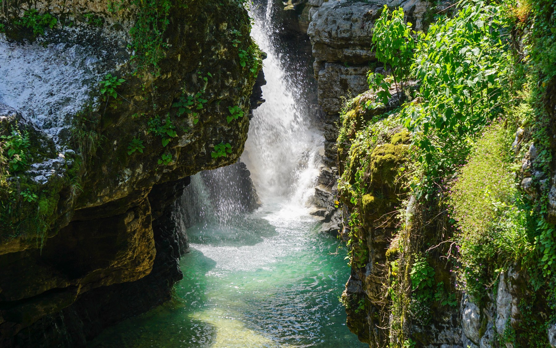 Bright turquoise pool and waterfall in Martvili Canyon
