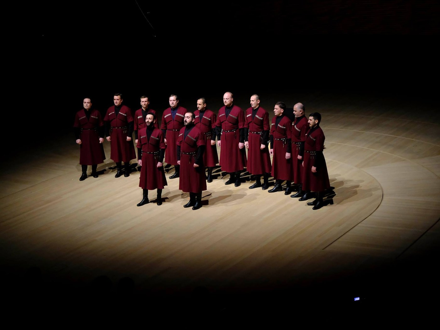 Ensemble Basiani performing in traditional maroon chokhas under a spotlight