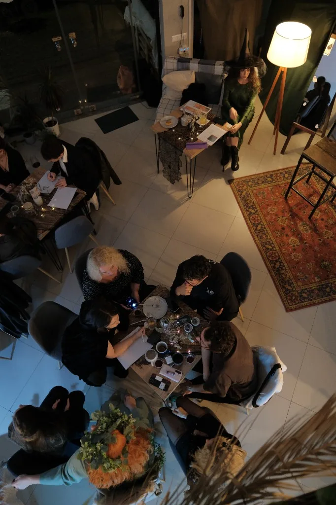 Guests writing at tables; a witch costume and Halloween décor in the room