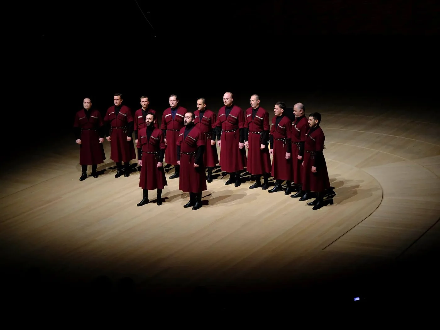 Ensemble Basiani performing in traditional maroon chokhas under a spotlight