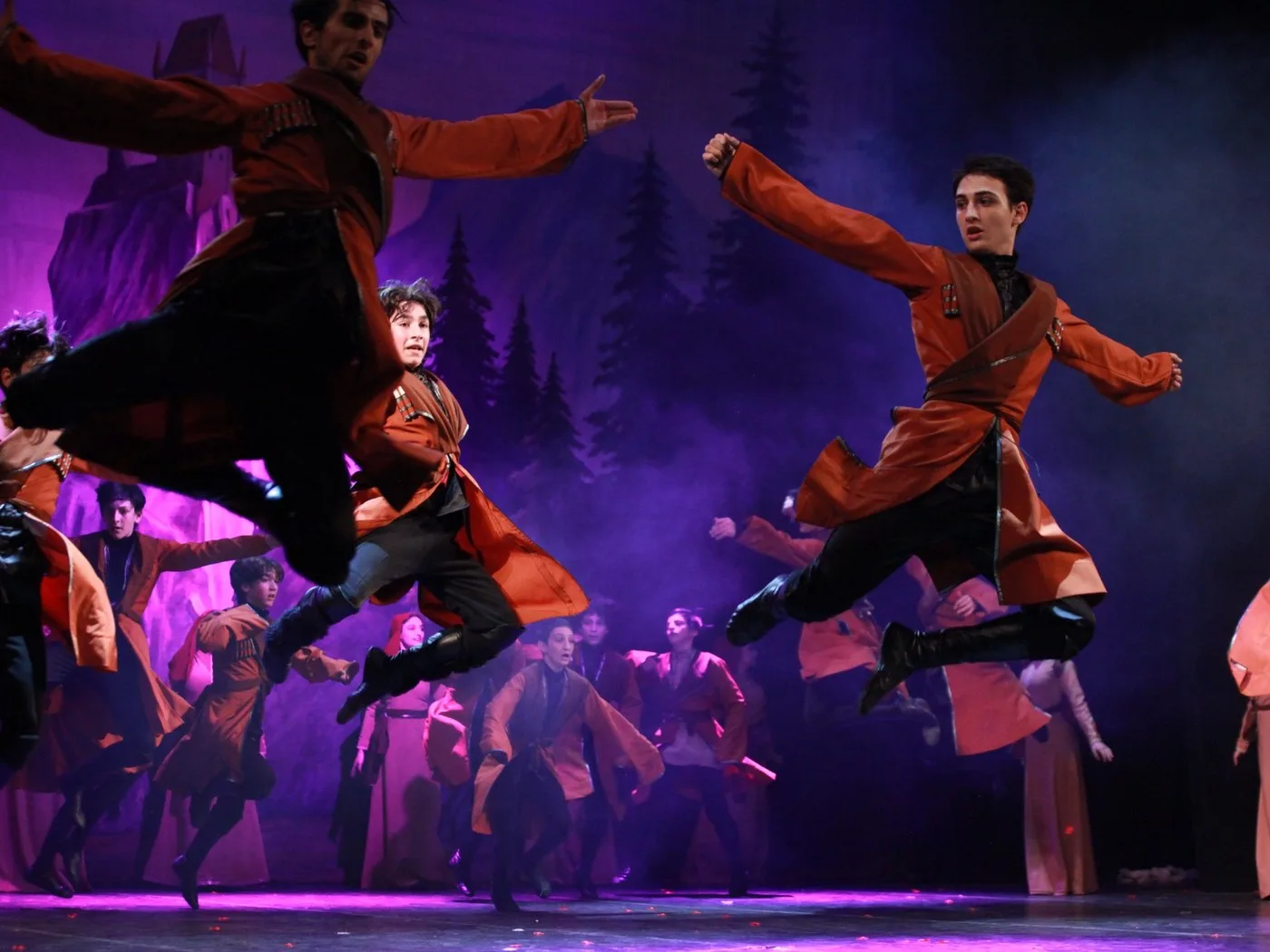 Georgian folk dancers leaping on stage in traditional chokha costumes